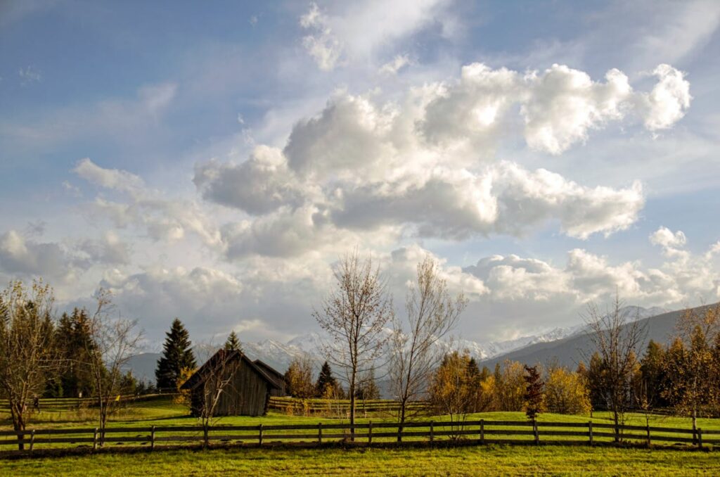 A panoramic view of a farm during sunset, with a tractor in the foreground.